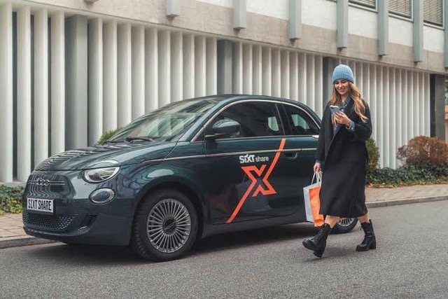 Frau neben einem elektrischen Kleinwagen mit Sixt-Signet