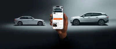 Smartphone mit der Sixt-Buchungsansicht zwischen zwei Fahrzeugen