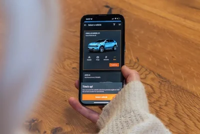 Hand hält ein Smartphone mit der Fahrzeugauswahl in der Sixt-App