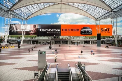 Flughafenhalle mit Sixt-Plakatwand „Calm before the storm“