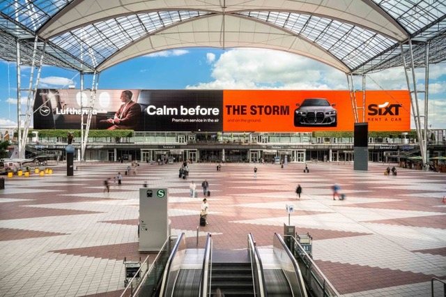 Flughafenhalle mit Sixt-Plakatwand „Calm before the storm“