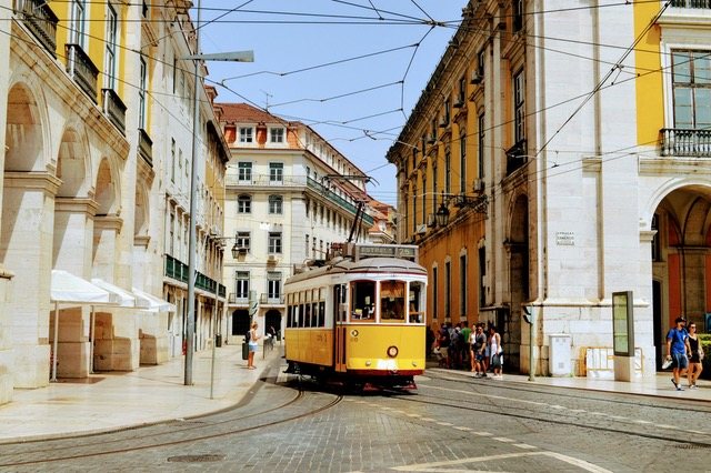 Gelbe Straßenbahn in einer engen Gasse in Lissabon